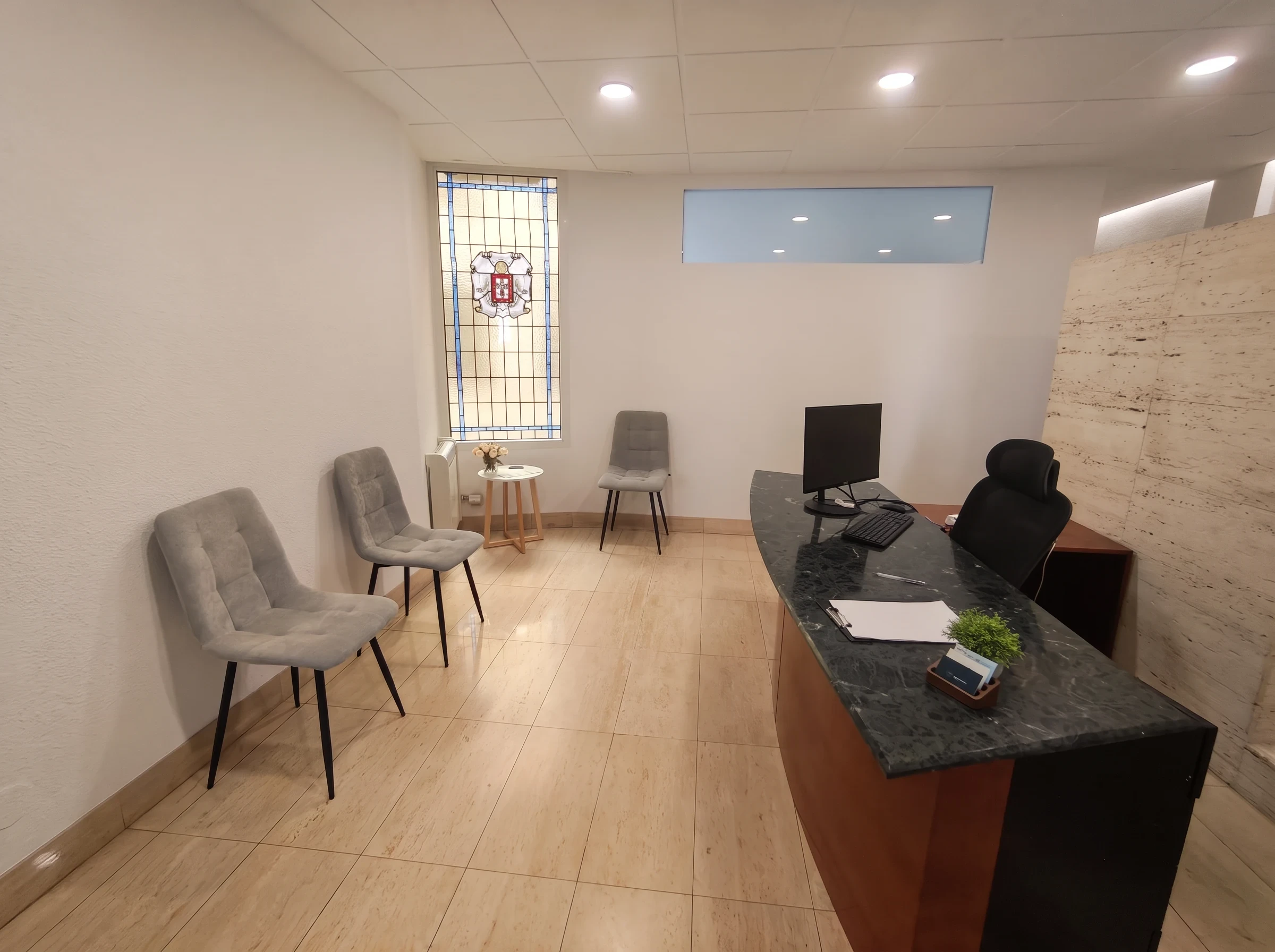 Recepción del centro Psiconervión Bilbao – Abando, con el mostrador de mármol verde, sillas de espera y una vidriera.