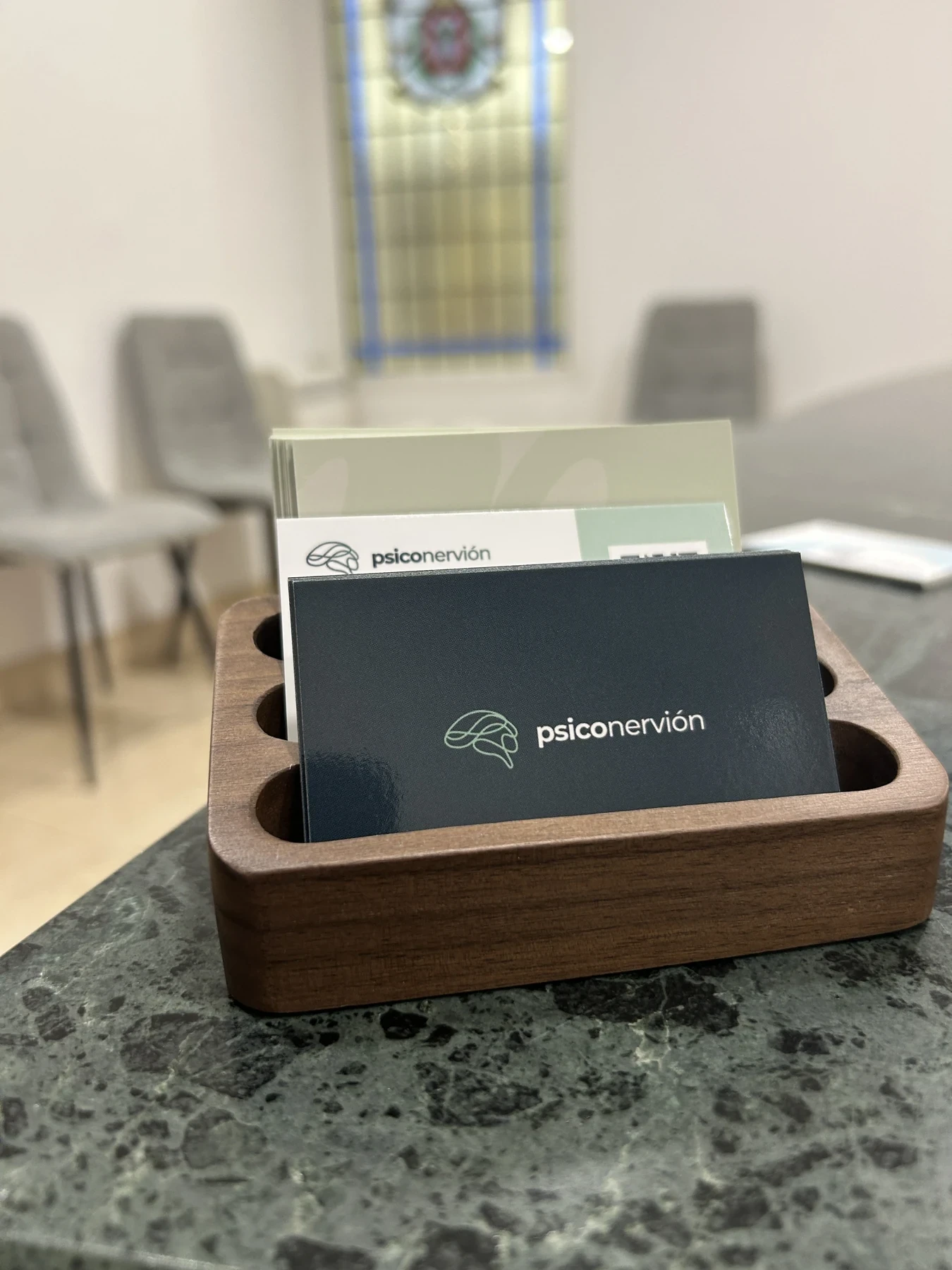 Tarjetero de madera con tarjetas de Psiconervión sobre el mostrador de mármol verde.