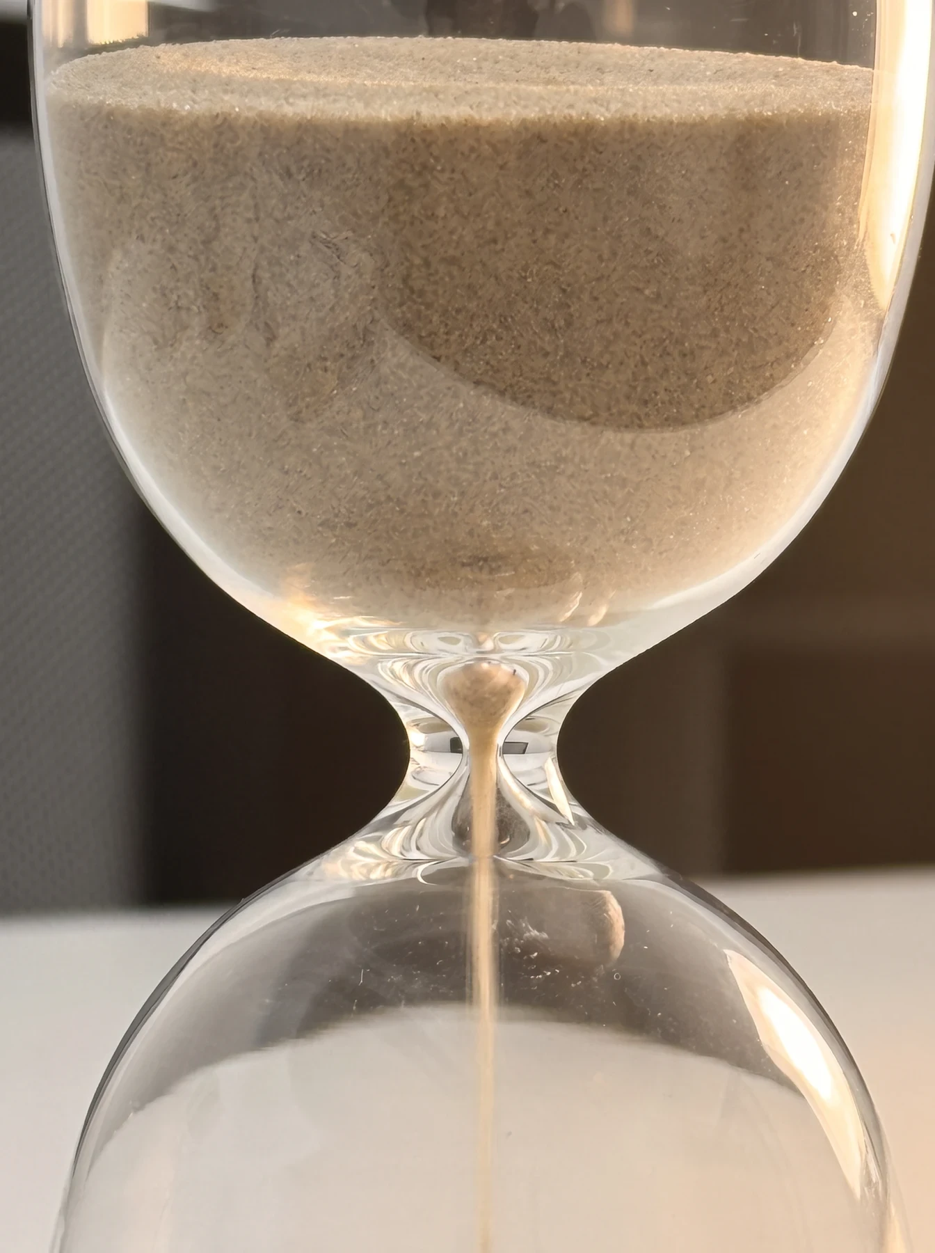 Primer plano de un reloj de arena sobre la mesa de la consulta.