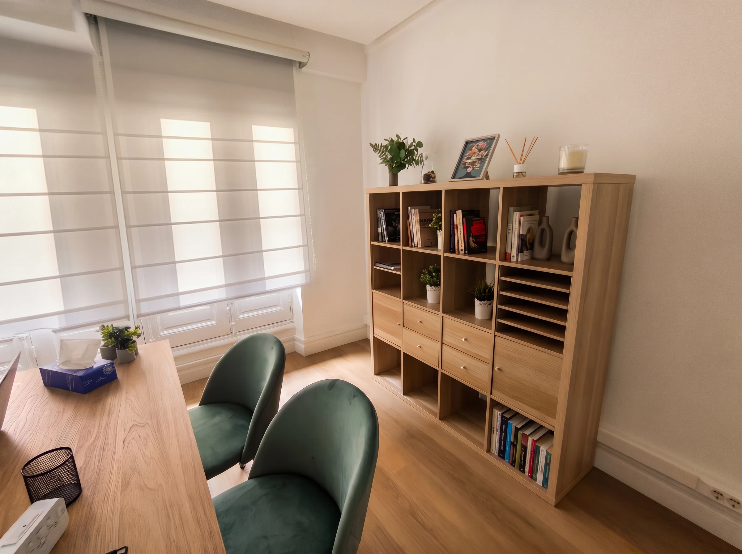 Consulta del centro Psiconervión Bilbao – General Concha, con el estor bajado sobre el ventanal, estantería de madera con libros y dos butacas verdes junto al escritorio.