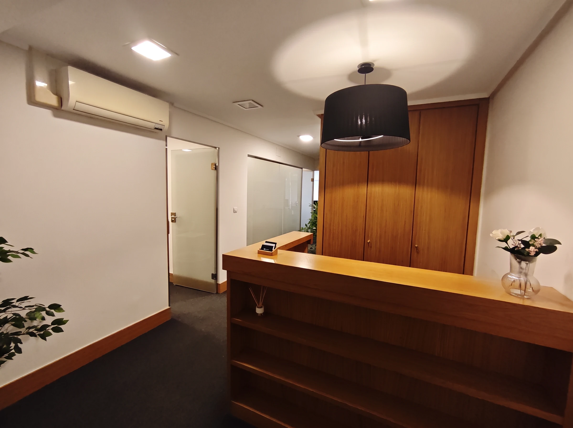 Recepción del centro Psiconervión Getxo – Las Arenas, con mostrador de madera, flores y lámpara colgante.