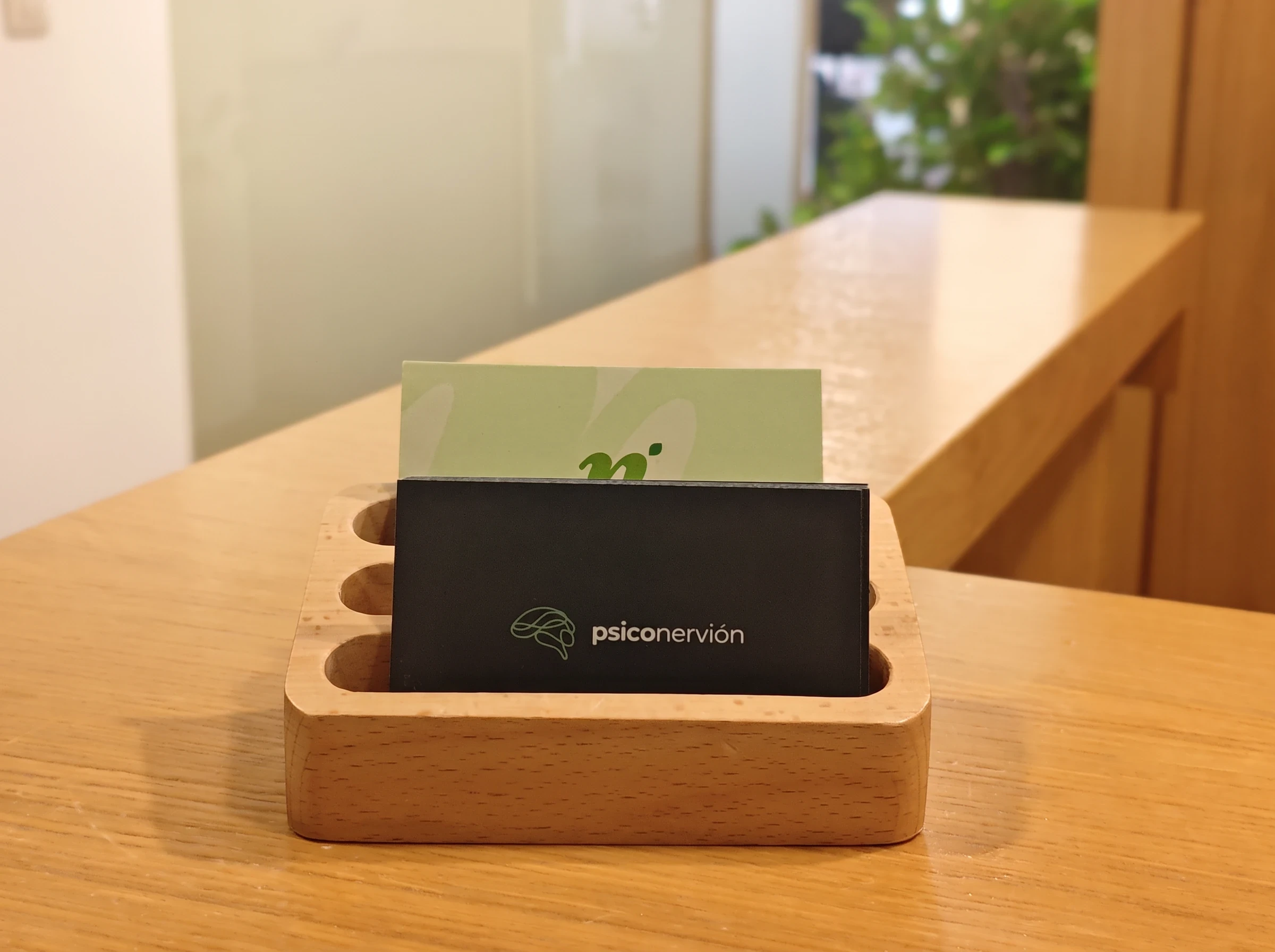 Tarjetero de madera con tarjetas de Psiconervión sobre el mostrador de recepción.