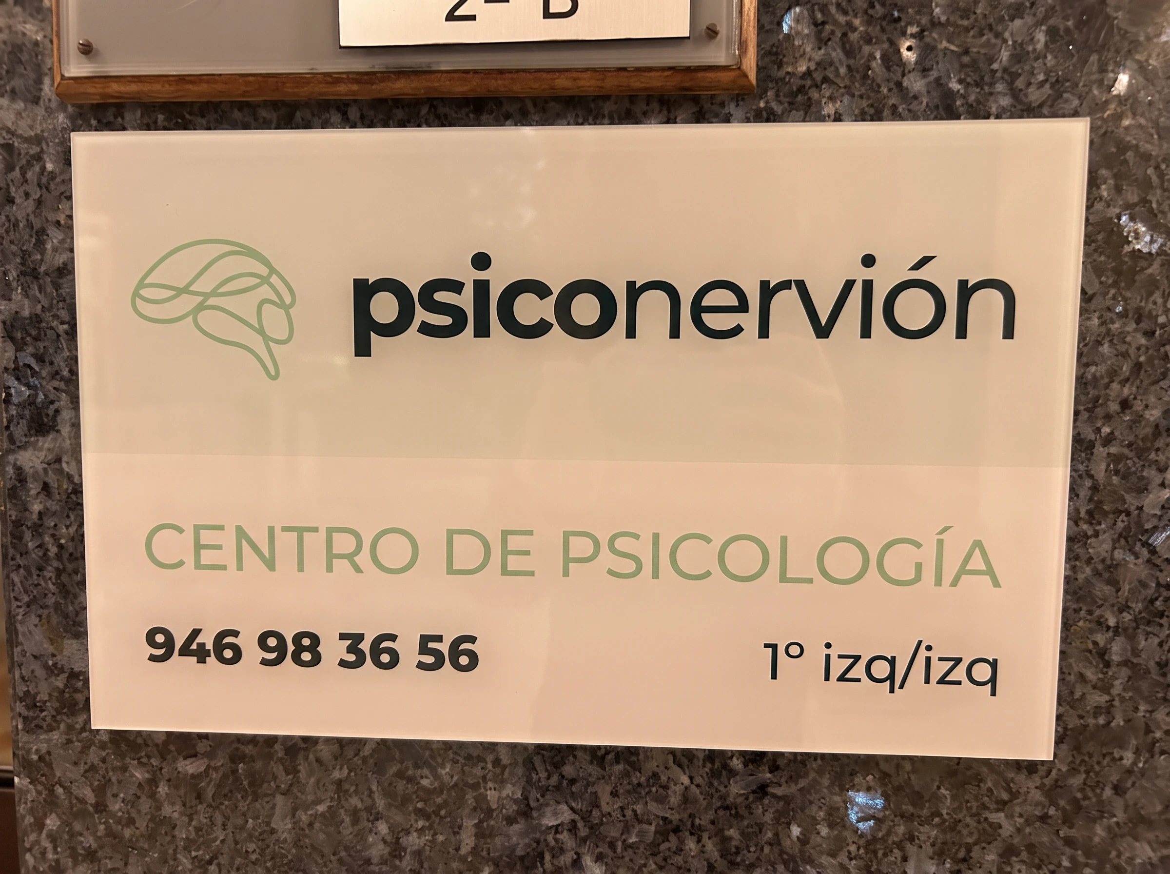 Placa de Psiconervión, centro de psicología, en el portal, con el teléfono y el piso: 1.º izquierda.