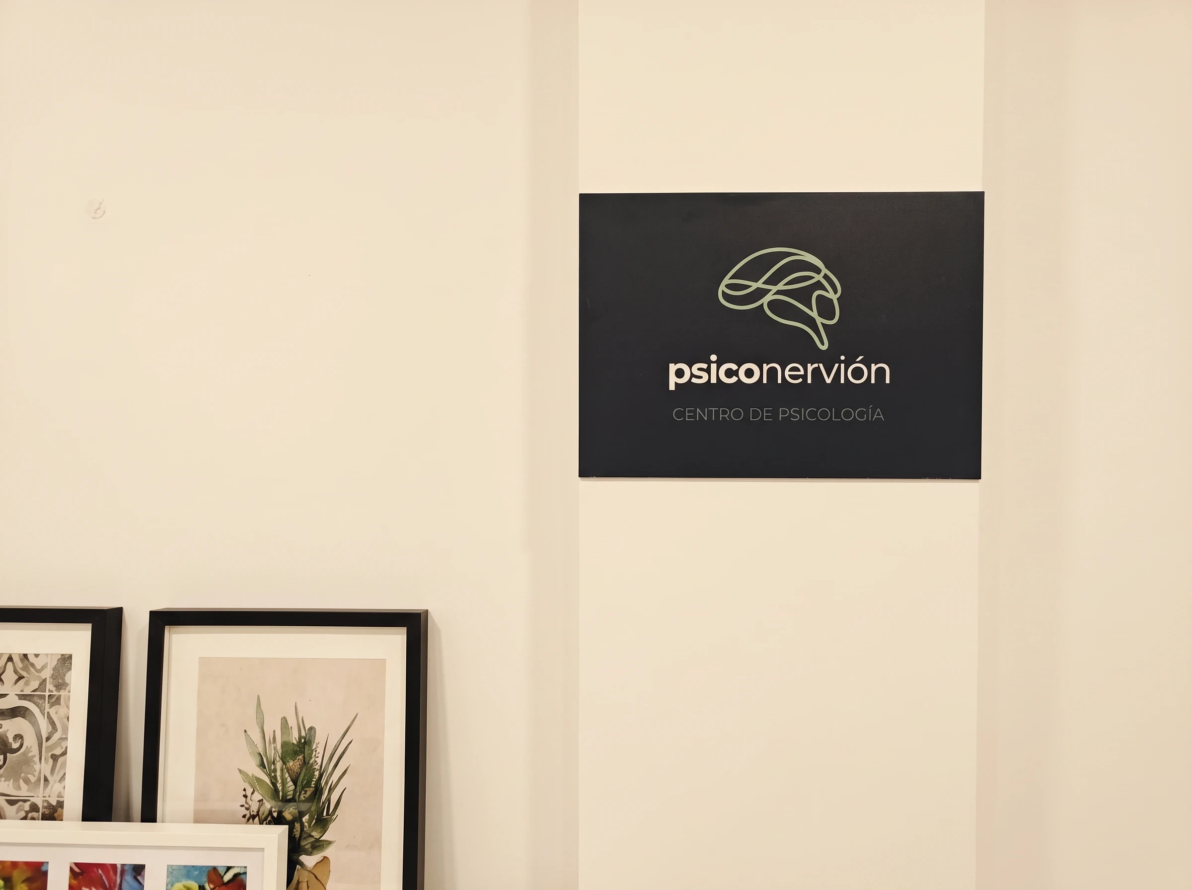 Panel con el logotipo de Psiconervión, centro de psicología, en la pared de la consulta.